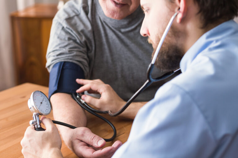 Médico realizando a medida de pressão arterial de paciente com hipertensão