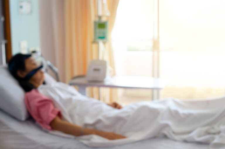 Covid-19: Mulher deitada em uma cama fazendo o uso de CPAP para respiração