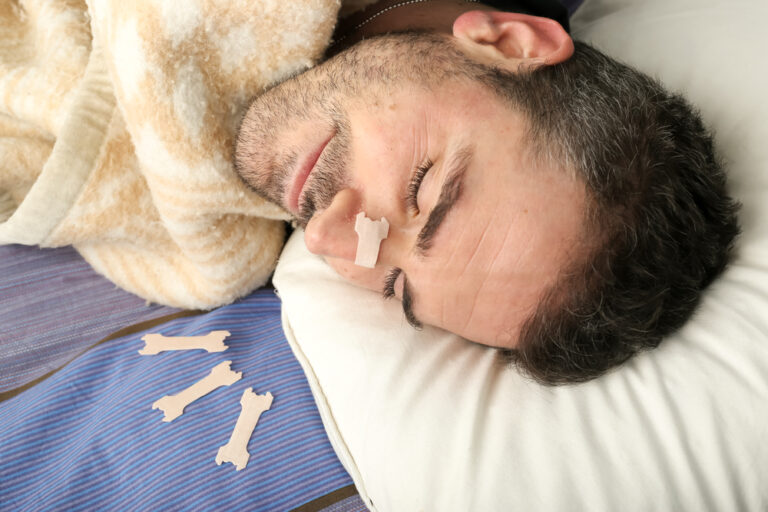 Homem jovem dormindo com ajuda de um dilatador nasal, para respirar melhor