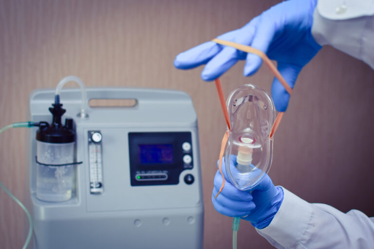 Mão médica com luvas segurando uma máscara VNI