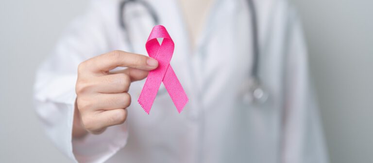 Imagem de uma pessoa segurando um laço rosa, que representa a conscientização sobre o câncer de mama.